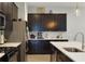 Modern kitchen featuring sleek dark cabinets, quartz countertops, stainless steel appliances, and an island with a sink at 220 Asterbrooke Dr, Deland, FL 32724