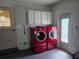 Convenient laundry area with modern red washer and dryer, plus overhead storage cabinets at 2204 Poinsettia Dr, Deland, FL 32724