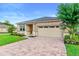 Charming home exterior showcases a brick driveway, lush lawn, and well-maintained landscaping at 2406 Kennington Cv, Deland, FL 32724