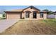 Tan single-story home with a two-car garage, brown roof, and tidy, drought-tolerant landscaping at 2448 Newmark Dr, Deltona, FL 32738