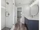 Bathroom with a shower, gray vanity with white countertop, wood-look floors, and round mirror at 2486 Shiprock Ct, Deltona, FL 32738