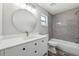 Bathroom featuring white vanity, round mirror, gray tile, and wood-look floors at 2486 Shiprock Ct, Deltona, FL 32738