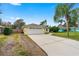 Home with an attached two-car garage and long driveway, featuring a manicured lawn and mature palms at 2526 Chester Ave, New Smyrna Beach, FL 32168