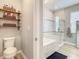 Bright main bathroom featuring toilet, decorative shelves, soaking tub, and tiled shower with glass door at 260 Teddy Rushing St, Debary, FL 32713