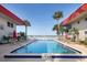 Community pool surrounded by palm trees with a peek of the water beyond at 2711 N Halifax Ave # 496, Daytona Beach, FL 32118