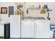 Close-up of washer and dryer with fridge and storage shelving in the garage at 276 Gala Cir, Daytona Beach, FL 32124