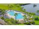 A serene pool area surrounded by palm trees, lush greenery, lounge chairs, and a beautiful lake at 276 Gala Cir, Daytona Beach, FL 32124