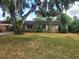 Single story house with stone detail, partially obscured by a tree and patchy grass at 2810 Kumquat Dr, Edgewater, FL 32141