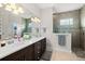 Elegant main bathroom featuring double sinks, a large mirror, and a tiled shower at 2814 S Asciano Ct, New Smyrna Beach, FL 32168
