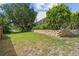 Wide backyard view with tiered retaining wall, screened-in porch, fountain, and surrounding lush foliage at 30 Reflections Village Dr, Ormond Beach, FL 32174
