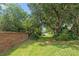 Private backyard view featuring mature shade trees, green grass, garden, and a water fountain at 30 Reflections Village Dr, Ormond Beach, FL 32174