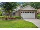 Charming single-story brick home with a well-manicured lawn, colorful flowerbeds, and an attached two-car garage at 30 Reflections Village Dr, Ormond Beach, FL 32174