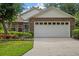 Charming brick home featuring a well-maintained lawn, mature landscaping, and an attached two-car garage at 30 Reflections Village Dr, Ormond Beach, FL 32174