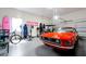 Spacious garage featuring a classic red car, workout equipment, surfboards, and ample space for storage and hobbies at 3698 Lower Park Rd, Orlando, FL 32814