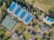Aerial view of pristine tennis courts next to a pool and parking lot with beautiful landscaping surrounding the amenities at 397 Quail Hill Dr, Debary, FL 32713
