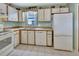 Functional kitchen featuring white appliances, wood-trimmed cabinets, and tile floors for easy maintenance at 416 N Blue Lake Ter, Deland, FL 32724
