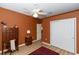 Bedroom with a ceiling fan, closet, wood floors, small desk, and orange paint at 470 Foxhill Dr, Debary, FL 32713