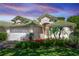 Charming home showcasing lush landscaping, a green tile roof, and a pristine white two-car garage at 470 Foxhill Dr, Debary, FL 32713