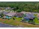 An aerial view shows the home with a manicured lawn, fenced yard, and screened pool, surrounded by mature trees and lush landscaping at 5463 Carmody Lake Dr, Port Orange, FL 32128