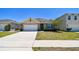 Charming single-story home featuring a well-manicured lawn and a vibrant turquoise-colored front door and window shutters at 5708 Sunbonnet Way, St Cloud, FL 34771