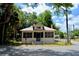 Charming bungalow-style home with screened porch, fenced yard, and mature trees under a blue sky at 580 Ronnoc Ln, New Smyrna Beach, FL 32168