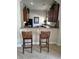 Kitchen bar with a light countertop and dark cabinets, complemented by two rattan bar stools, great for casual dining at 6043 Strada Isle Way, Orlando, FL 32835