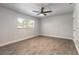 Bright bedroom with wood-look tile floors, neutral walls, ceiling fan, and natural light at 612 Moonpenny Cir, Port Orange, FL 32127