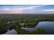 Expansive aerial view of a wooded community along a waterway at sunset with a distant skyline at 6317 Palmas Bay Cir, Port Orange, FL 32127