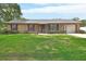 Charming brick home with a well-manicured lawn, mature bushes, and attached garage at 672 Swarthmore Dr, Deland, FL 32724