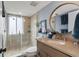 Well-lit bathroom features a glass-enclosed shower, neutral tile, round mirror and a modern vanity at 6847 S Atlantic Ave, New Smyrna Beach, FL 32169