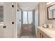 Beautifully updated bathroom features a glass shower and vanity with wooden cabinetry and ample lighting at 6847 S Atlantic Ave, New Smyrna Beach, FL 32169