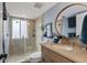 Well-lit bathroom features a glass-enclosed shower, neutral tile, round mirror and a modern vanity at 6847 S Atlantic Ave, New Smyrna Beach, FL 32169