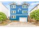 Charming three-story blue home with a dolphin design, white trim, and a white garage door at 6847 S Atlantic Ave, New Smyrna Beach, FL 32169