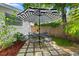 Backyard with a patio set and umbrella, surrounded by lush greenery and charming landscaping at 708 Wayne Ave, New Smyrna Beach, FL 32168