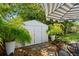 Cozy backyard featuring a storage shed, lush plants, a patio umbrella, and outdoor seating area at 708 Wayne Ave, New Smyrna Beach, FL 32168