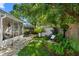 Lush backyard with a storage shed, mature trees, a screened-in porch, and manicured garden at 708 Wayne Ave, New Smyrna Beach, FL 32168