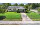 A charming home features a vibrant green lawn, complemented by a chain-link fence at 708 Wayne Ave, New Smyrna Beach, FL 32168