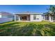 Lush backyard with green grass and view of the home's rear exterior and covered patio at 887 Lake Hill Way, Deland, FL 32724