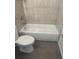 Bathroom with a white toilet next to a tub and neutral-toned tiling at 926 Clover St, Deland, FL 32720