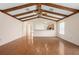 Spacious living room with wood beam ceiling, view of kitchen, and gleaming wood floors at 11094 Se 173Rd Ln, Summerfield, FL 34491