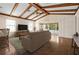 Staged living room featuring wood beam ceiling, ceiling fan, and sliding glass door to the lanai at 11094 Se 173Rd Ln, Summerfield, FL 34491