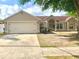 Charming single-story home with a well-manicured lawn, mature tree, and attached two-car garage at 1311 Fallwood Dr, Deltona, FL 32725