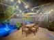 Enjoy evening dining in the screened patio with ambient lighting, wood table, and garden views at 1311 Fallwood Dr, Deltona, FL 32725