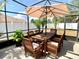 Enjoy outdoor dining in the screened patio featuring a wooden table, chairs, and an umbrella at 1311 Fallwood Dr, Deltona, FL 32725