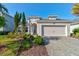 Charming home showcasing a manicured lawn, paver driveway, and attached two car garage at 133 Azure Mist Way, Daytona Beach, FL 32124