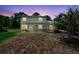 Charming two-story home with a covered front porch, surrounded by lush trees under a colorful dusk sky at 1560 7Th Ave, Deland, FL 32724