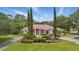 Charming single-story home featuring a vibrant red roof and lush landscaping, set against a backdrop of mature trees and blue skies at 1641 Timber Hills Dr, Deland, FL 32724