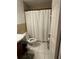 Tiled bathroom featuring a toilet, sink, and shower with a white curtain at 2219 Howland Blvd, Deltona, FL 32738