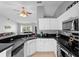 Galley kitchen featuring white cabinets, black counters, stainless steel appliances, and a double sink at 2416 Candlewick St, Deltona, FL 32738