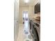 Modern laundry room with front-load washer and dryer, cabinet storage, and tiled flooring at 2435 Pawtucket Pass, Mount Dora, FL 32757
